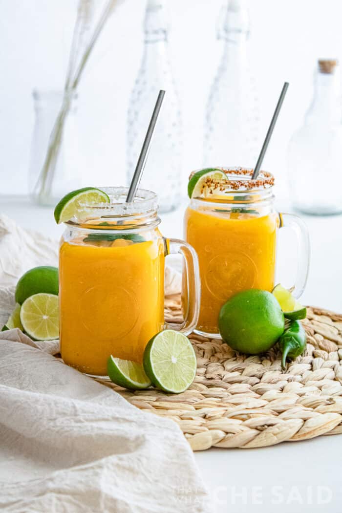 two mason jar glasses with frozen mango margarita in them, one has salt rim the other a tajin rim